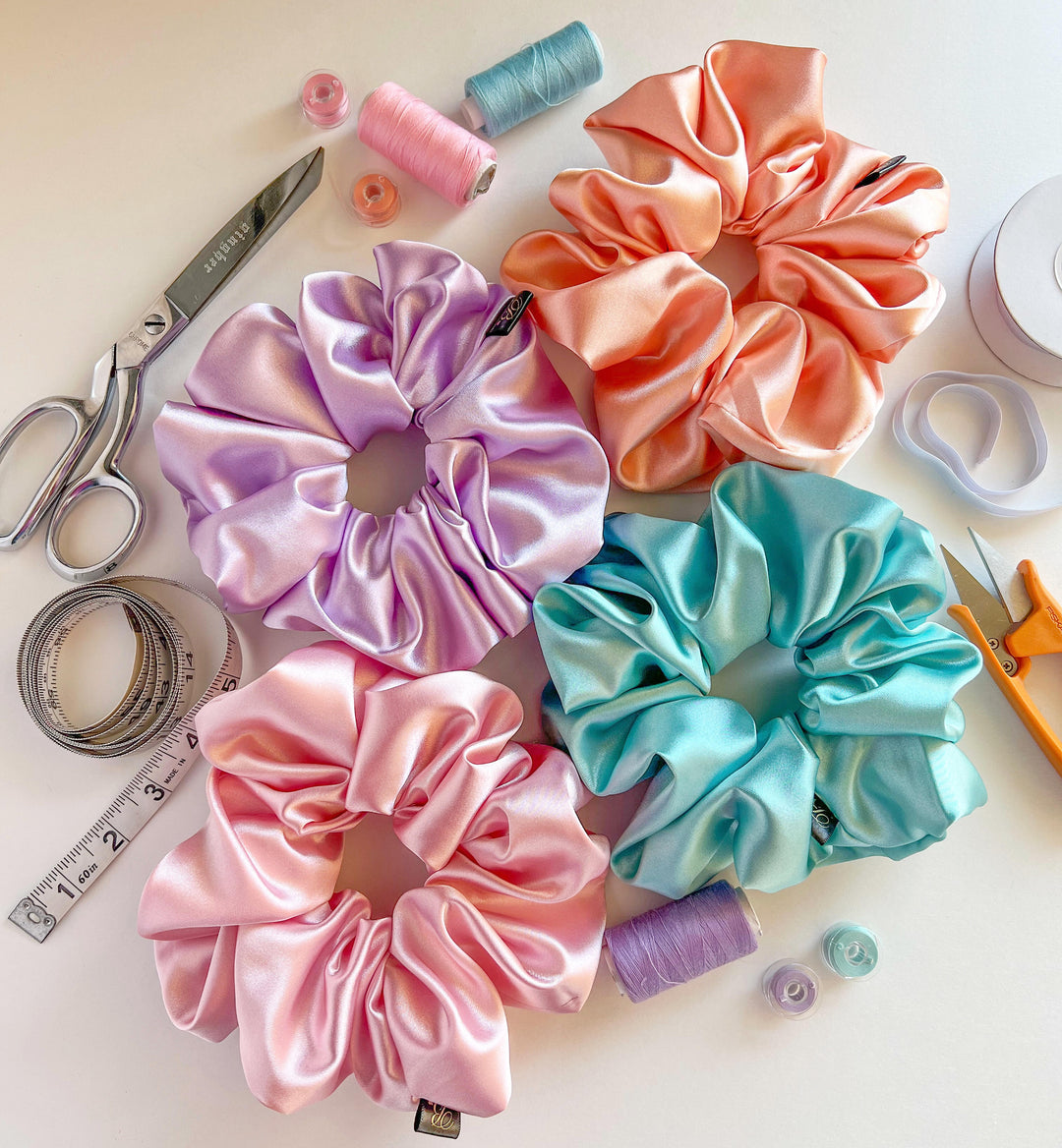 Flat lay composition of handmade scrunchies alongside sewing tools, representing craftsmanship and attention to detail at B. LUVV & CO.